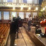 Channel 13's Gina Gaston taping a promo spot on the stage of Vienna's Musikverein