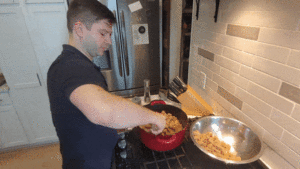 Man stirring stuffing in a kitchen.