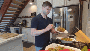 Man eating stuffing while standing in a kitchen.